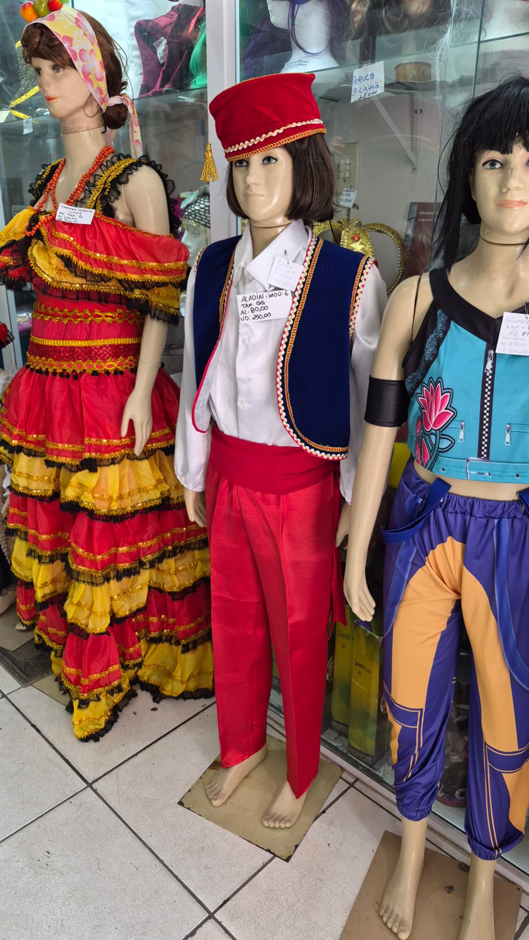 Fantasias infantis de Carmen Miranda, Aladdin e personagem colorida em manequins